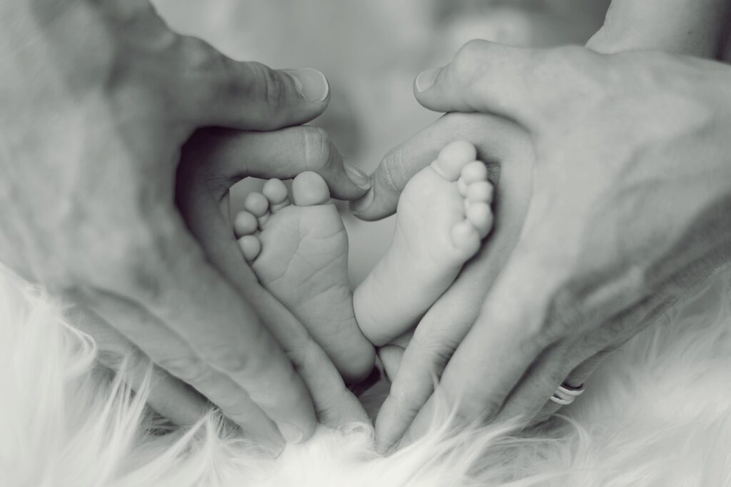Infant and parents hands around feet in a heart shape